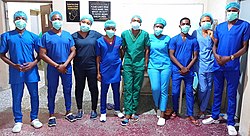 A color photograph of nine health professionals, all wearing scrubs and facemasks