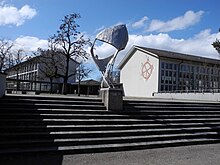 Robert Lienhard (1919–1989) Spiel mit dem Wind, Drachenflieger 1957. Aluminiumguss. 3. 10m x 1. 80m x 1. 20m. Robert Wehrlin (1903–1964), Sgraffito Glücksrad 1958, 5 Meter Durchmesser. Schulhaus Hohfurri, Winterthur.