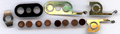 Einzel­teile eines Kupfer­oxydul-Gleich­richters: Kupfer­scheiben mit Oxidschicht, dunkle Scheiben aus Hartpapier isolieren die Bügel­feder