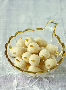 A small glass bowl containing a number of confectionary items, each of which are also small, round, white, with a small nut-like object sticking out