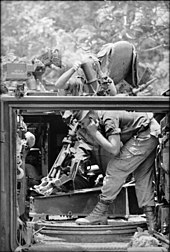 Black and white photo of a soldier firing an artillery piece from a tracked vehicle