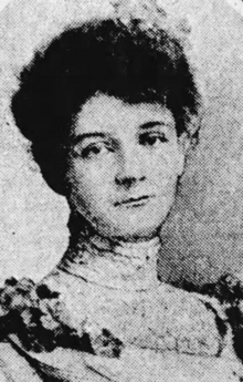 A young white woman with dark hair in an updo, wearing a dress with a high lace collar