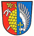 Gemeinde Trosdorf Gespalten von Rot und Blau; vorne eine halbe goldene Weintraube mit Stiel und Blatt am Spalt, unterlegt von zwei schräg gekreuzten silbernen Karsten; hinten ein silberner Flügel mit silberner Hand, die ein goldenes Kleeblattkreuz hält.[40]