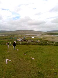 Marked walkway across a meadow, with large tents in the background