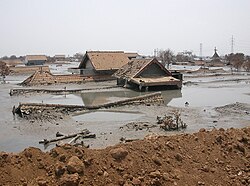 Mehrere Häuser stehen bis zu den Dächern in einem See aus Schlamm, der durch den Schlammvulkan Lusi verursacht wurde.