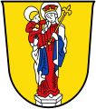 Stadt Altötting In Gold auf silbernem Sockel stehend eine golden gekrönte und silbern nimbierte Madonna in rotem Gewand und silbernem, innen blauem Mantel, auf dem rechten Arm das rot gewandete, einen goldenen Apfel haltende, silbern nimbierte Kind; in der Linken ein goldenes Lilienzepter.