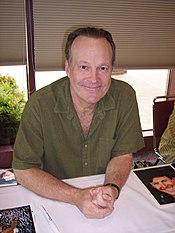 A 58-year-old man with dark grey hair, smiling at the camera.