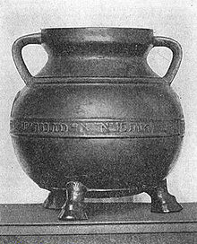 A two-handled footed cauldron-shaped vessel with a Hebrew inscription running along the middle