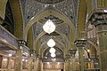 Some chandeliers hanging from the ceiling of a corridor in the mosque