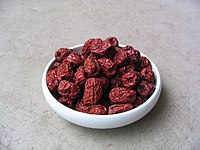 A bowl of reddish-purple, oval-shaped fruits with raisin texture.
