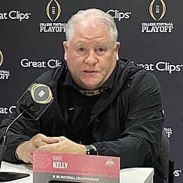 A football coach speaks in front of a microphone.