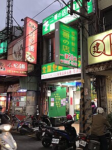 A street in Taipei with several signs in Chinese. One sign reads 二哥の店, lit. 'Second Brother's Shop', using の instead of 的.