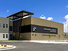 Photo of part of a tan/gray building labeled "Captain Gabriel L. Navarrete Middle School" with artwork of a knight helmet