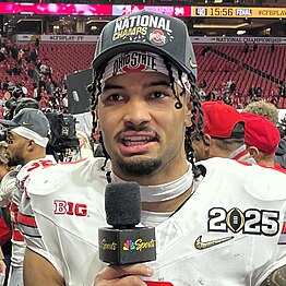 A football player talking to microphone on a football field.