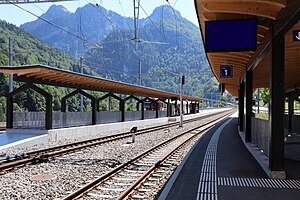 Train platforms with a wooden shelter and a white and red train