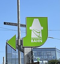 Green drawing of one Schloßbergbahn car inside the white filled outline of the Grazer Clocktower on a green background. Beneath saying "Schloßbergbahn"