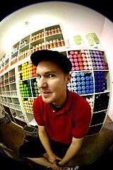 A man wearing a red shirt with a black cap, looking directly at the camera