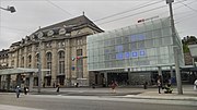 27.–28. KW Der Bahnhof St. Gallen mit dem alten Gebäude auf der linken Seite, dem neugestalteten Bahnhofsplatz und dem Glaskubus mit binärer Uhr.