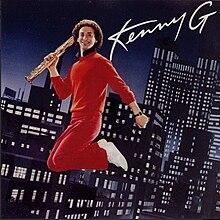 A man in a red jumpsuit is shown in mid-air holding a saxophone in his right hand, over a backdrop of a city at night with lit-up buildings. At the top right is written "Kenny G".