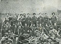 Black-and-white photo of a group of 24 armed men