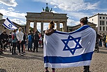 İsrail bayrağı taşıyan iki kişi birlikte Brandenburg Kapısı'nın karşısında duruyor