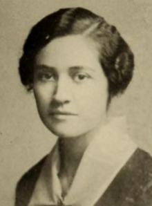 A young white woman with dark wavy hair parted on the side