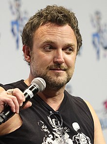 Jason Liebrecht, with a mustache and goatee, talking into a microphone