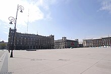 Picture of a square and three buildings in the background. Zócalo/Tenochtitlan station's entrance is in a corner of the square.