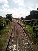 Two parallel train tracks with a disused train platform on the left side and a new platform on the right side