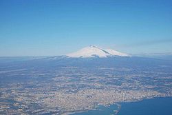 An aerial view of the metropolitan city around Catania. Mount Etna is the peak at a distance.