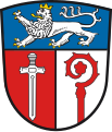 Landkreis Ostallgäu Unter blauem Schildhaupt, darin ein schreitender, golden gekrönter und golden bewehrter silberner Löwe, gespalten von Rot und Silber; vorne ein gestürztes silbernes Schwert, hinten ein wachsender roter Abtstab.