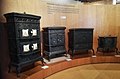 Gusseiserne Öfen. Ganz links: Ofen „Vogesen“ mit emaillierten Motivplatten, erstes Viertel des 20. Jahrhunderts; ganz rechts: ältester Ofen des Museums aus dem Jahr 1778