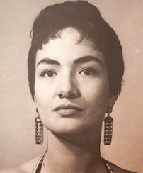 A young Latina woman, with short dark hair, olive skin, and dark eyebrows, wearing drop earrings