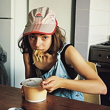 Stella Donnelly eating from a bowl of noodles on a table.