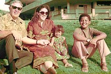 Photo of a young Obama sitting on grass with his grandfather, mother, and half-sister.