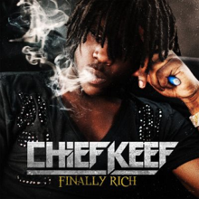 Chief Keef holding an e-Cigarette in his left hand clenched into a fist while exhaling smoke exhaust.