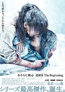 Kenshin Himura holds Yukishiro Tomoe, who lies on the ground, in a snowy landscape.