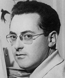 Three-quarter profile, black and white, Press shot of young, clean-shaven man with spectacles and dark hair.