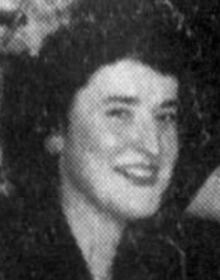 A smiling young white woman with dark hair, wearing a dark dress or blouse