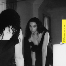 Black and white picture of Charli XCX looking at herself in the mirror