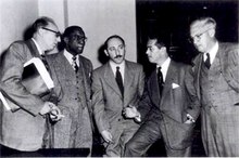 Five well-dressed men standing and conversing.