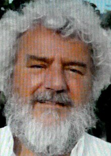 Colour Press photo of a smiling, full-bearded man with fluffy, curly white hair