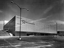 A black-and-white photo of a two-level department store. Visible on the store is signage reading "Rollman's"