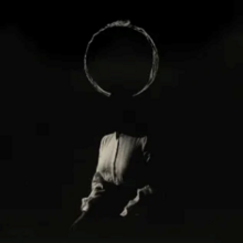 A dark silhouette-like picture of Ethel Cain with a giant ring above her head.