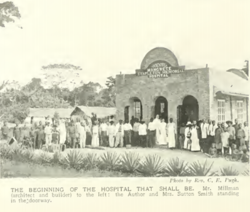 Mission members in front of early hospital buildings, c. 1909